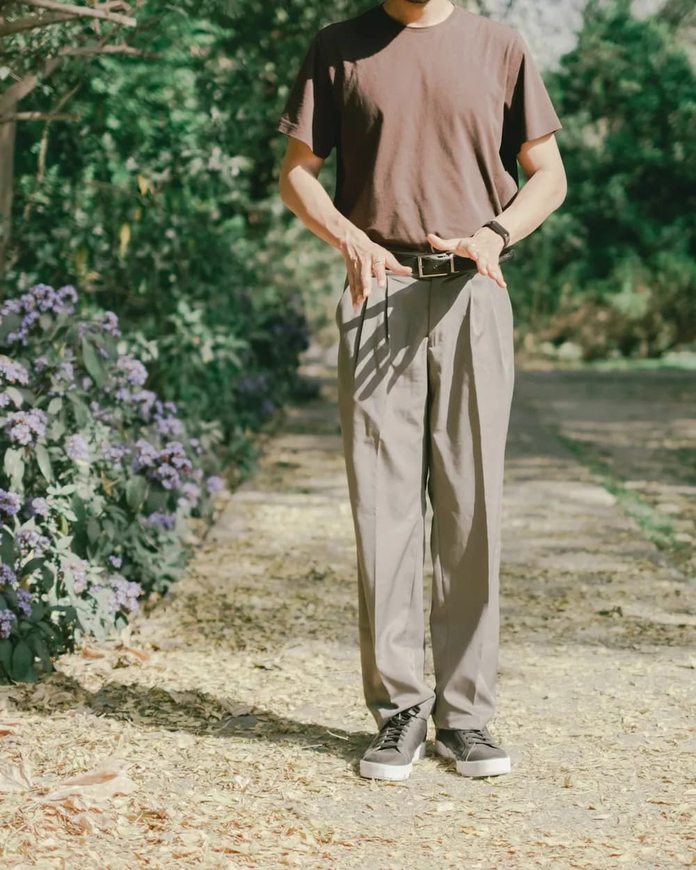 A man in pleated stone chinos and a brown tee